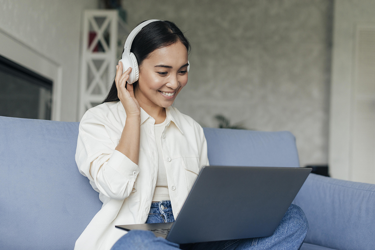 smiley-woman-with-headphones-working-laptop